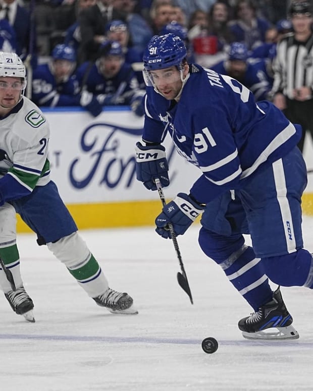 Nov 12, 2022; Toronto, Ontario, CAN; Toronto Maple Leafs forward John Tavares (91) controls the puck as Vancouver Canucks forward Nils Hoglander (21) closes in during the third period at Scotiabank Arena. Mandatory Credit: John E. Sokolowski-USA TODAY Sports